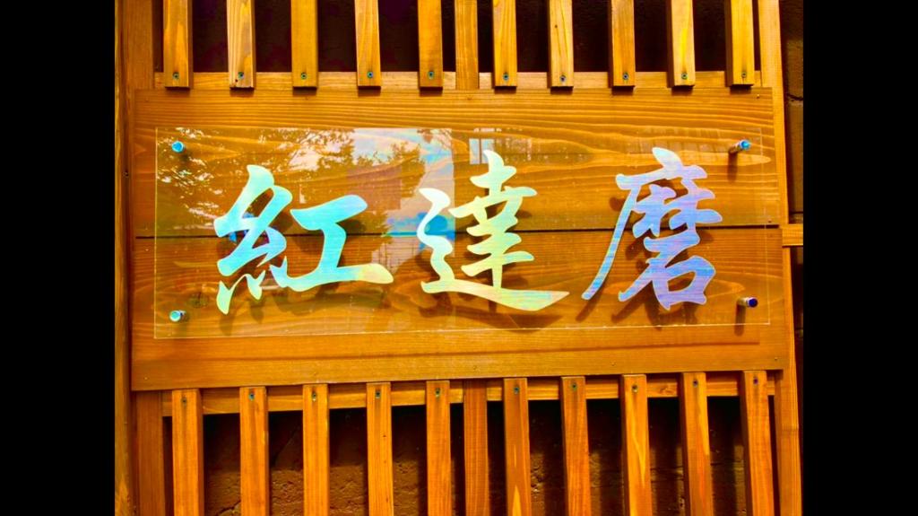 a fence with chinese writing on the side of it at Benidaruma - Ichigo Daifuku in Kyoto