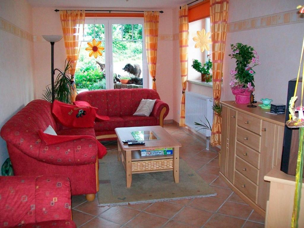 Sala de estar con 2 sofás rojos y mesa de centro en FeWo Mareike en Hanerau-Hademarschen