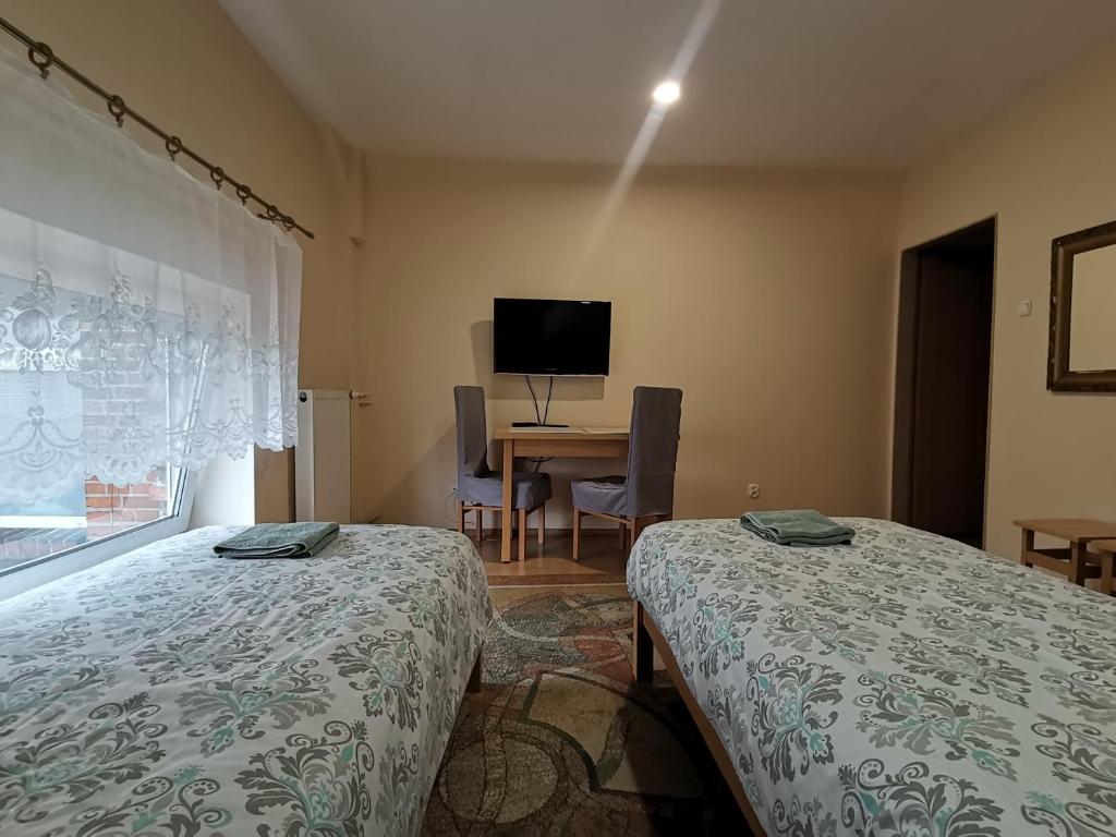 a room with two beds and a table with a television at Hostel "Na Bocianowie" in Bydgoszcz