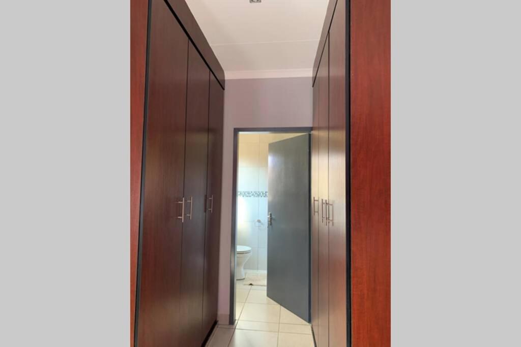 baño con armarios marrones, aseo y espejo en Rhino House with 3 bedrooms next to Pilanesberg and Sun City, en Mogwase