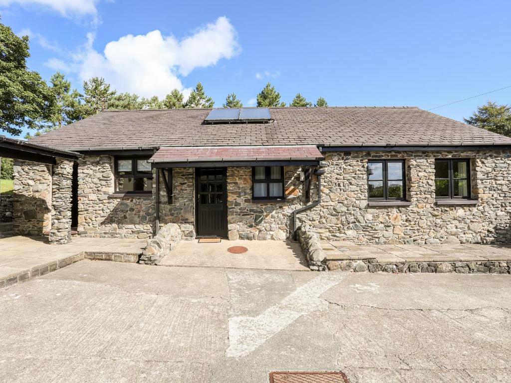 a stone house with a driveway in front of it at Bryn Eira Tack Room in Llanfairpwllgwyngyll