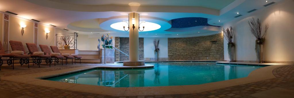 una piscina in un hotel con sedie e soffitto di Active Hotel Monte Giner a Mezzana