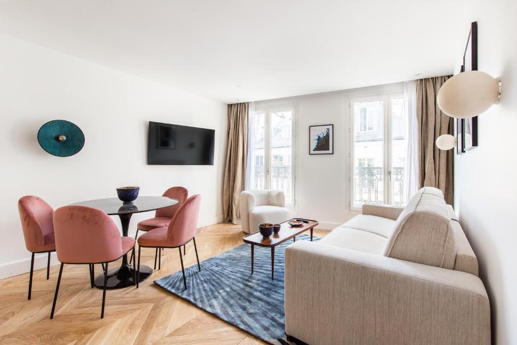 ein Wohnzimmer mit einem Sofa, einem Tisch und Stühlen in der Unterkunft Quartier Libre - Saint Georges in Paris