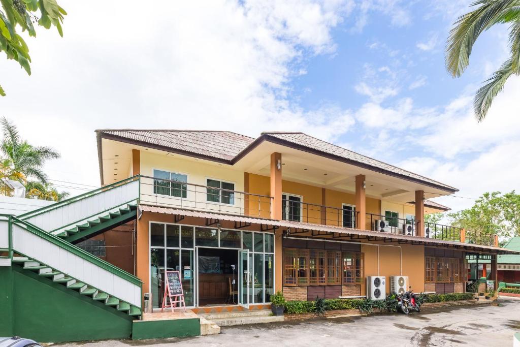 a house with a balcony and palm trees at เฮือนคำรีสอร์ท บูติค โฮเทล แม่สาย เชียงราย in Chiang Rai