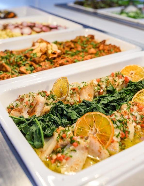 a tray of food with fish and greens and oranges at River Rock Hotel in Ayia Napa