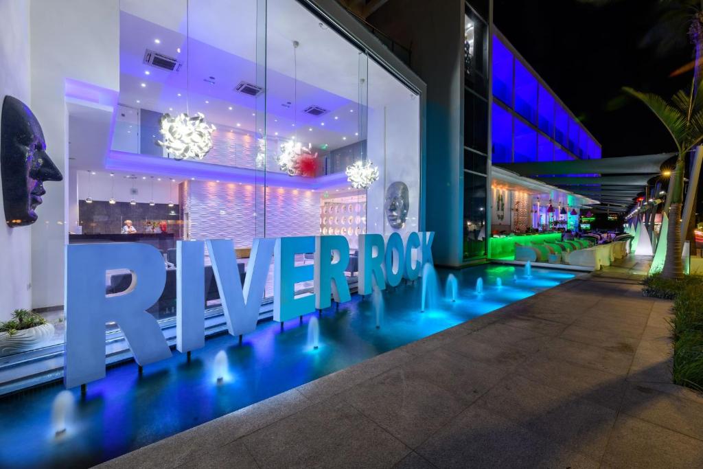 a store with a blue lighted sign on the side of a building at River Rock Hotel in Ayia Napa