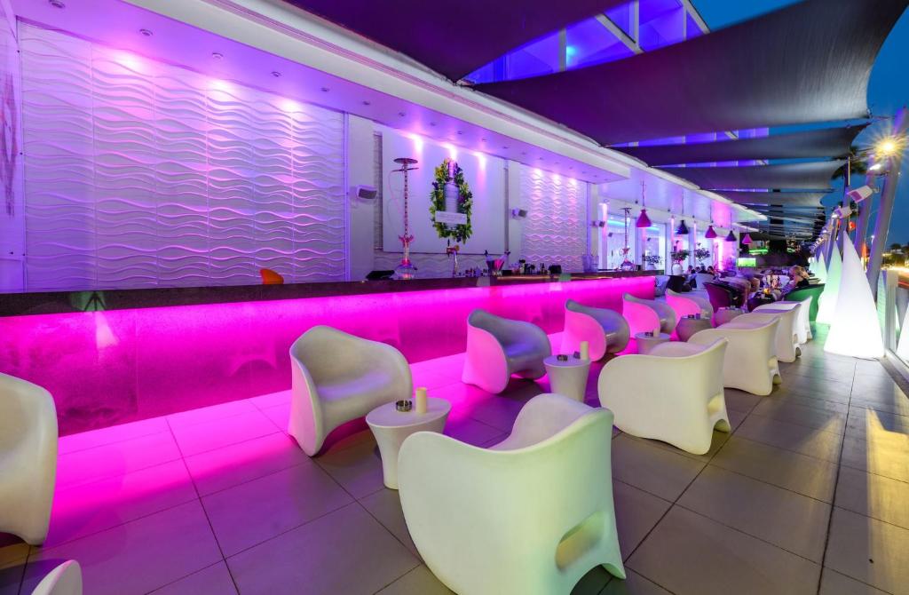 a bar with white chairs and pink lighting at River Rock Hotel in Ayia Napa