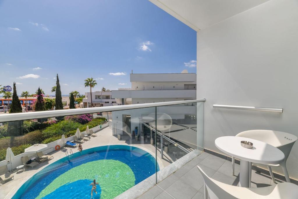 an apartment balcony with a swimming pool and chairs at River Rock Hotel in Ayia Napa