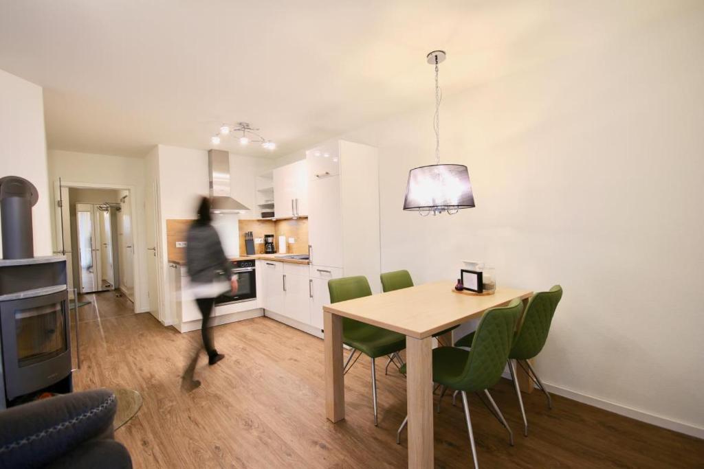 a kitchen and dining room with a table and green chairs at Kirschgarten 3 in Kellenhusen