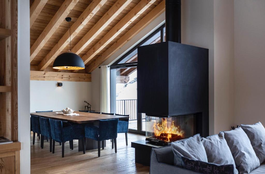a living room with a fireplace and a dining table at Chalet le Blue Moon in L'Alpe-d'Huez