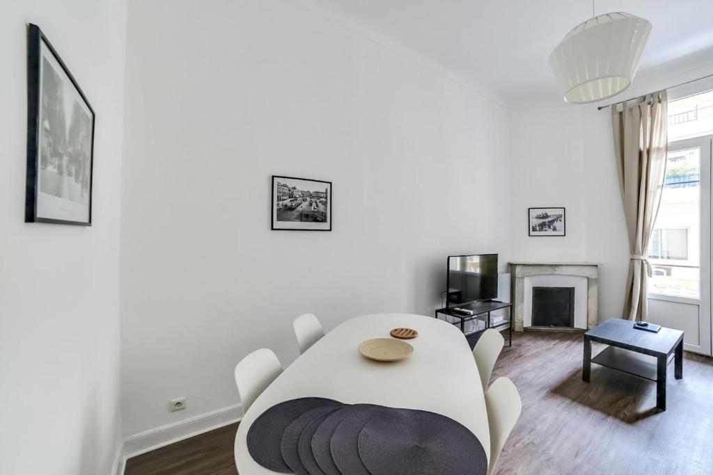 - un salon blanc avec une table et une cheminée dans l'établissement Very nice typical apartment between Carré dOr and Old Nice Welkeys, à Nice