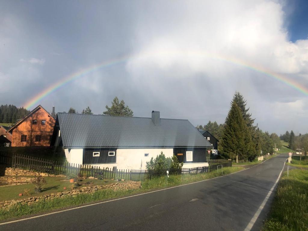 a rainbow over a house on the side of a road at Chata Violka Kvilda in Kvilda