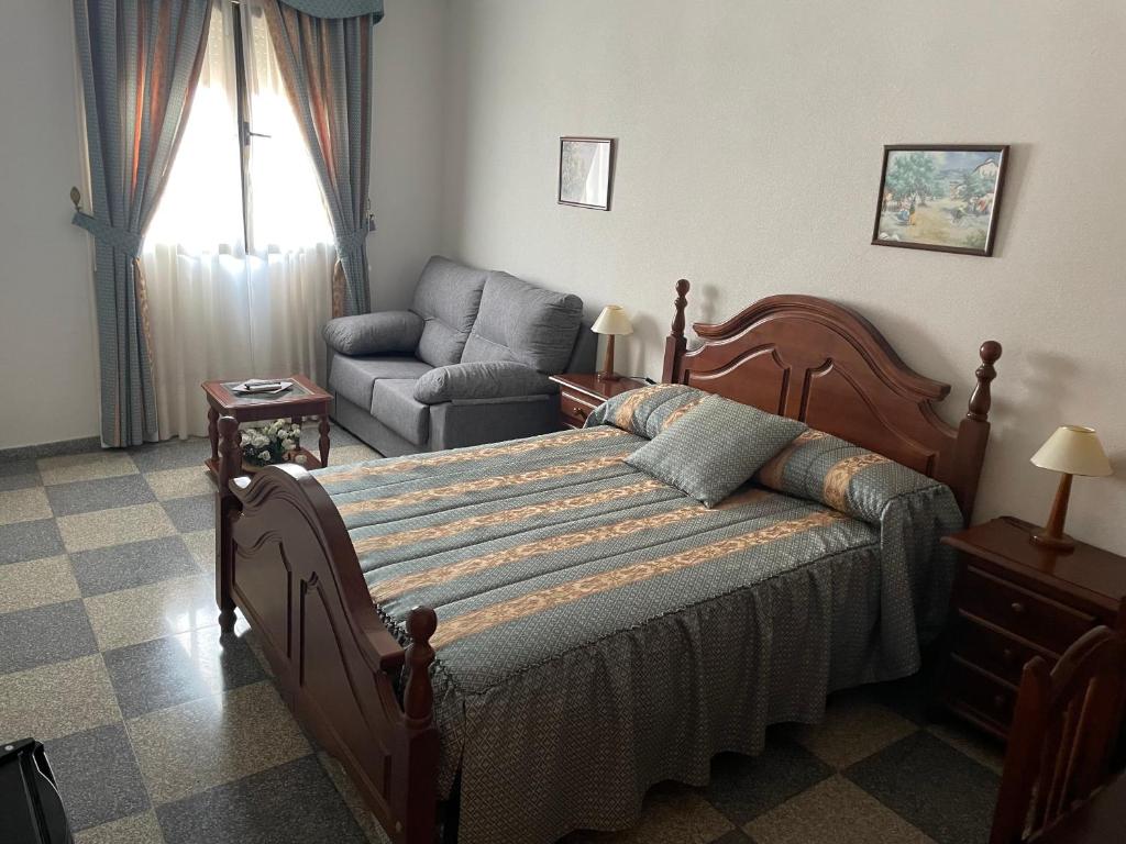 1 dormitorio con 1 cama, 1 silla y 1 sofá en Hostal Las Palomas, en La Calzada de Calatrava