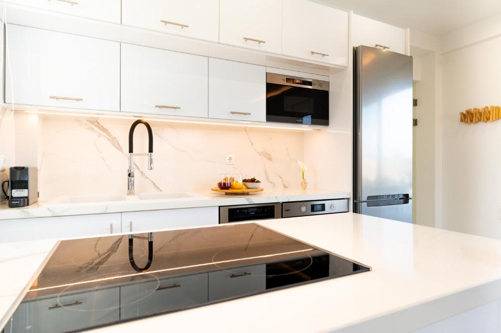 a kitchen with white cabinets and a stainless steel refrigerator at Sardines Luxury Villas in Analipsi