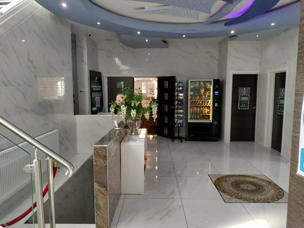 a lobby with white marble walls and stairs with vases of flowers at Torbay Court Hotel in Paignton