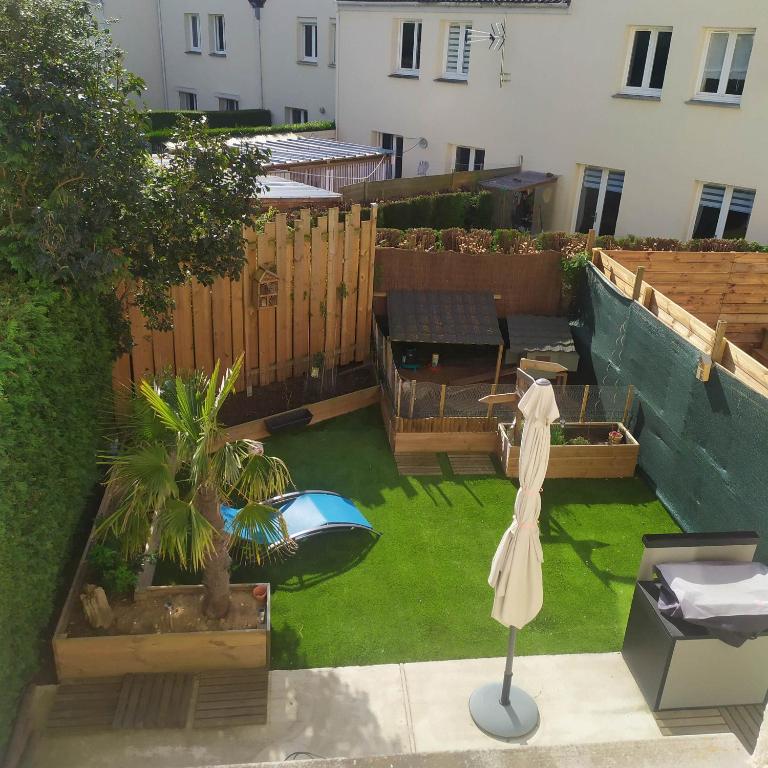 un petit jardin avec une table et une clôture dans l'établissement L'écluse des Fontinettes, maison de ville atypique, à Arques