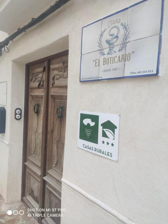 a sign on the side of a building with a door at La Casa del Boticario in Alcalá del Júcar