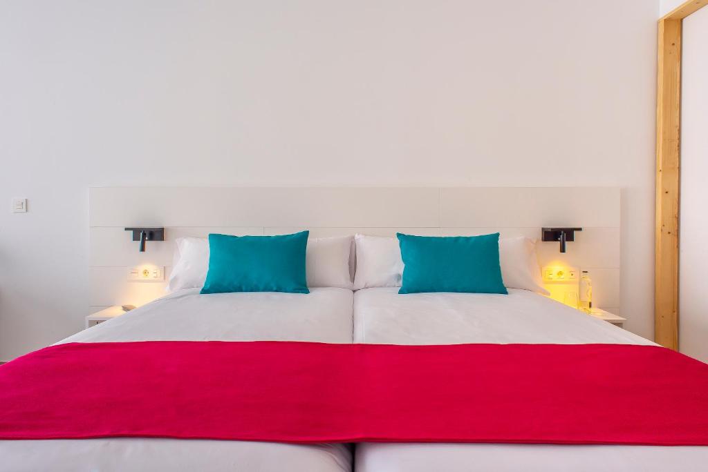 a large white bed with red and blue pillows at Hotel Taimar in Costa Calma