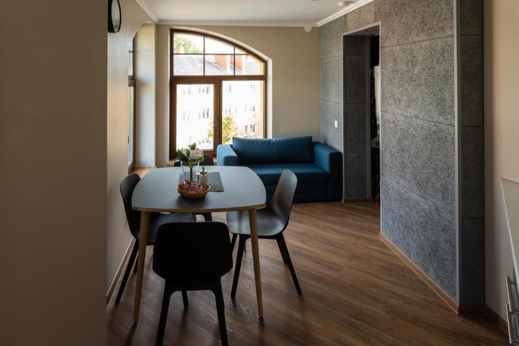 uma sala de estar com uma mesa e um sofá azul em Apartamenti Alūksne em Alūksne