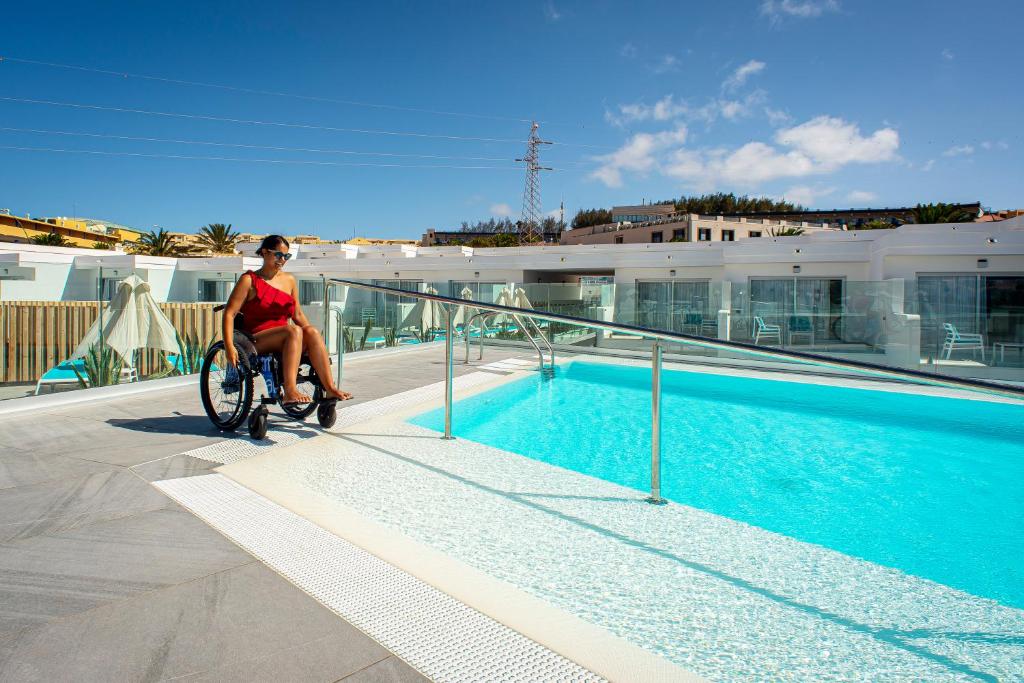 a woman riding a bike next to a swimming pool at Hotel Taimar in Costa Calma
