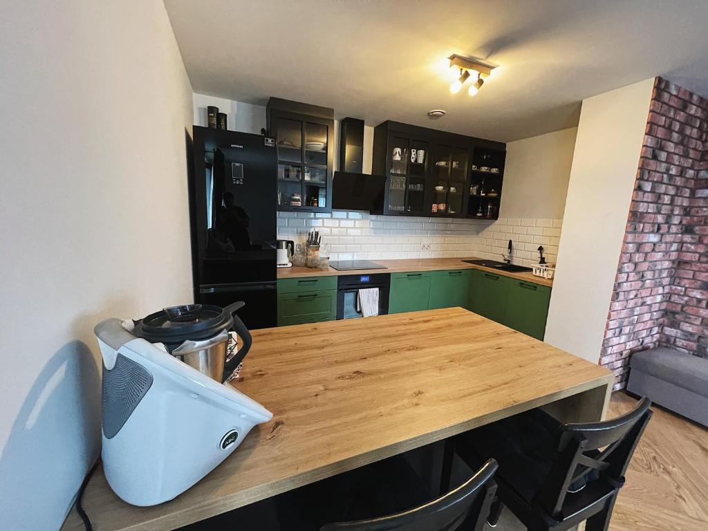 une cuisine avec une table en bois et des armoires vertes dans l'établissement Apartamenty Pod Kątami, à Kamienica