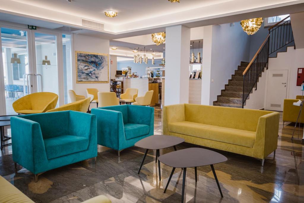 a lobby with yellow and blue chairs and tables at Principe Alogna Hotel & SPA in Altavilla Milicia