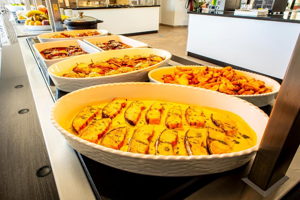 a buffet with several trays of food on a counter at Hotel Taimar in Costa Calma