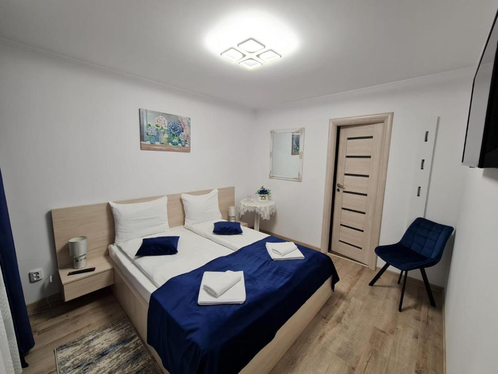 een slaapkamer met een bed en een blauwe stoel bij Splendid House in Făgăraş