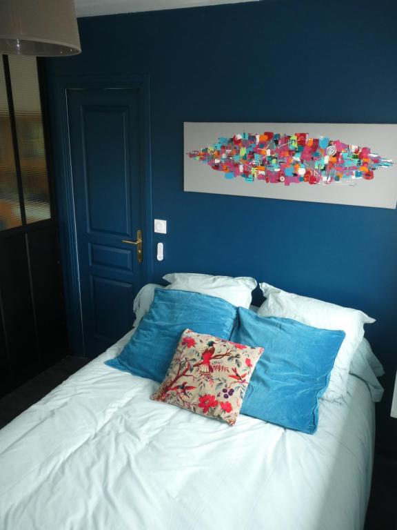a white bed with blue walls and two pillows at Studio Cosy proche Grand-Champ Home Sweet Home in Plumergat
