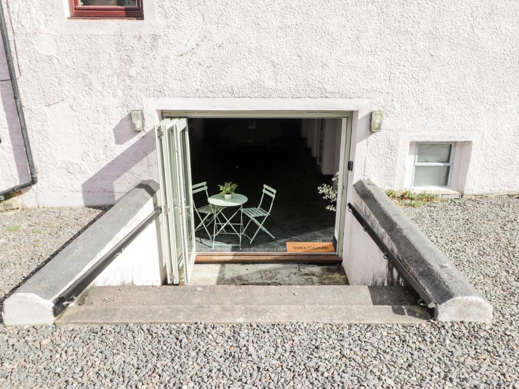 a door to a building with a table and a chair at Mary Ann Apartment in Inverness