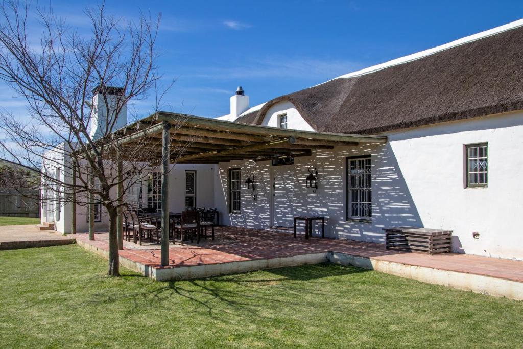 ein weißes Haus mit einer Veranda und einer Terrasse in der Unterkunft Anna Beulah Farm in Durbanville