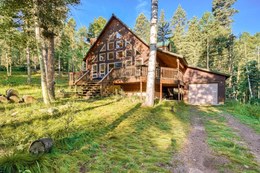 a log cabin in the woods with a dirt road in front at Casa en Verde in Angel Fire