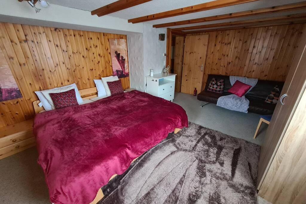 a bedroom with a large bed in a room with wooden walls at 2. Zimmer im Nü-Hus in Arosa