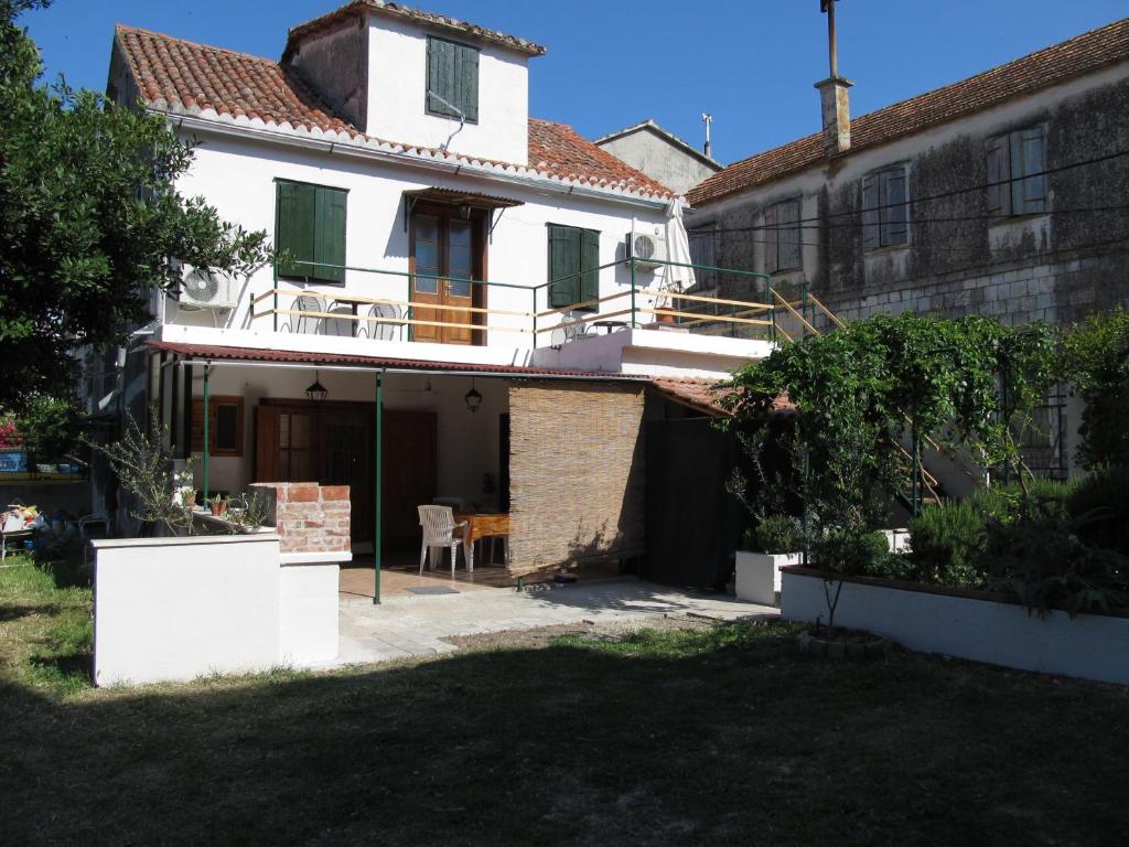 une maison blanche avec des volets verts et une cour dans l'établissement Guesthouse Trogir Proto, à Trogir