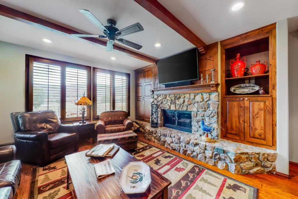 a living room with a stone fireplace and a ceiling fan at Arrowhead Condos in Edwards