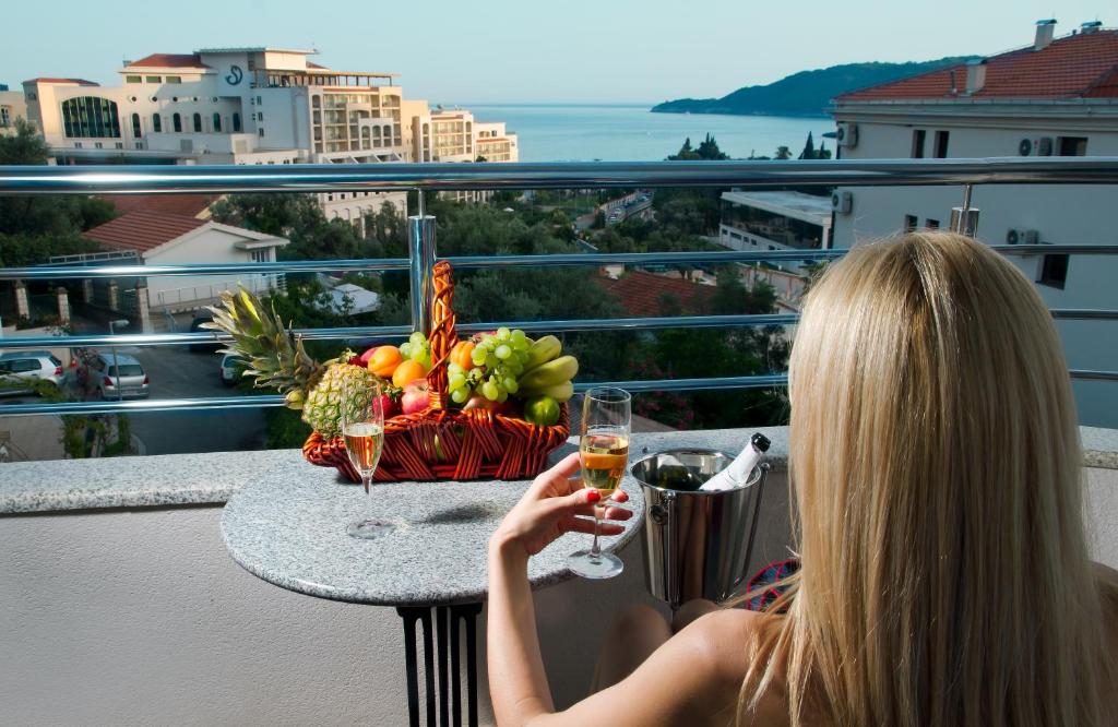 a woman sitting on a balcony with a glass of wine at Dolce Vita in Budva