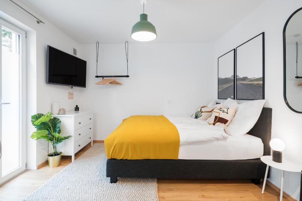 1 dormitorio con 1 cama con manta amarilla en limehome Ingolstadt Bauhofstraße en Ingolstadt