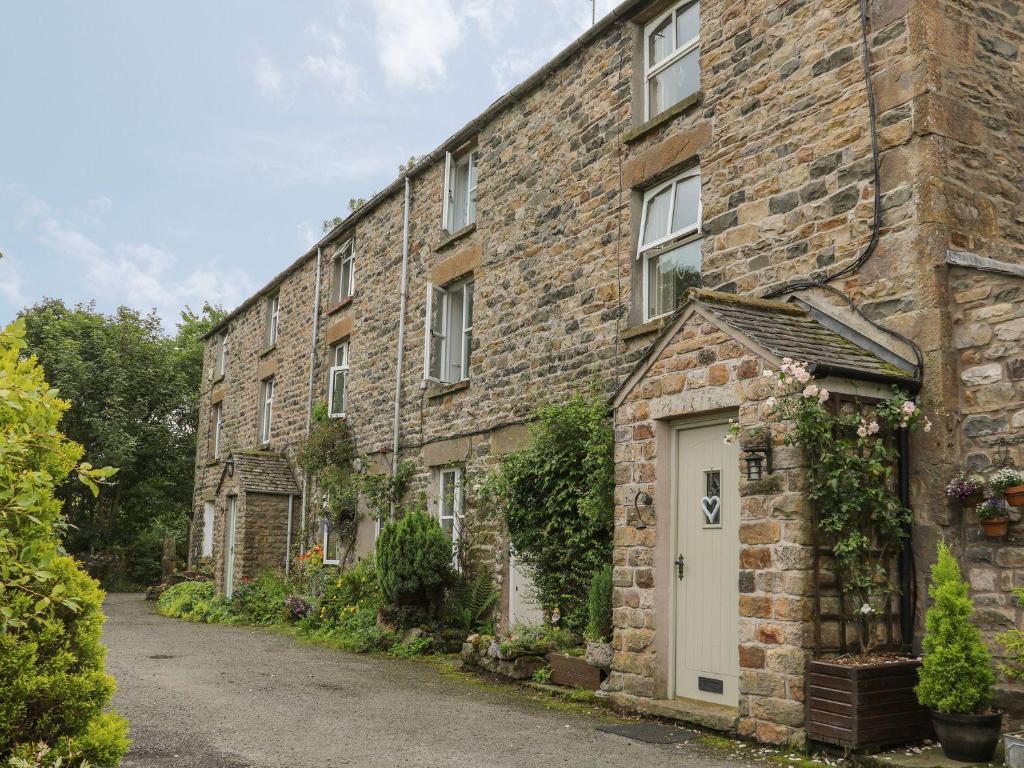 un vecchio edificio in mattoni con una porta bianca di 2 Farfield Row a Sedbergh