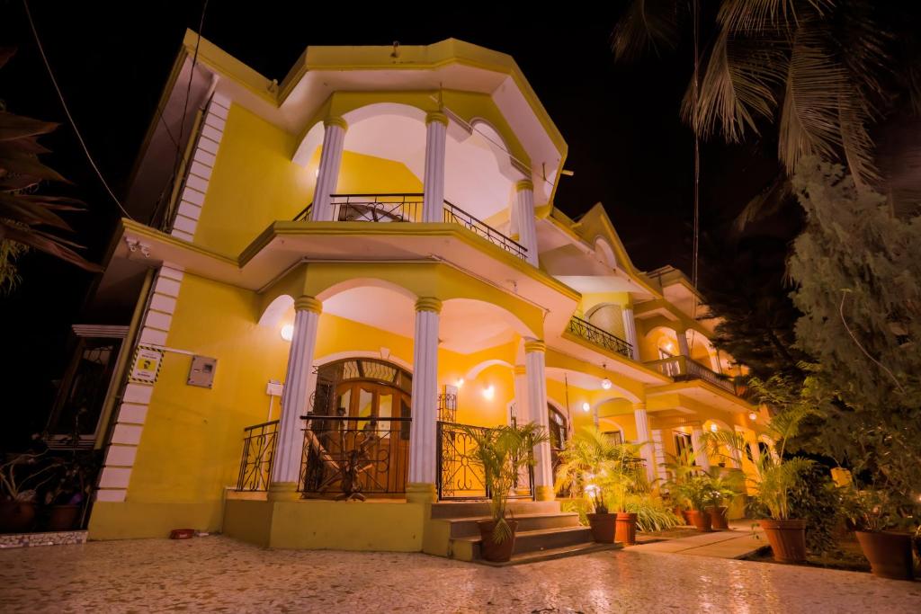 Un grand bâtiment jaune avec balcon est disponible la nuit. dans l'établissement Primavera Holiday Homes, à Candolim