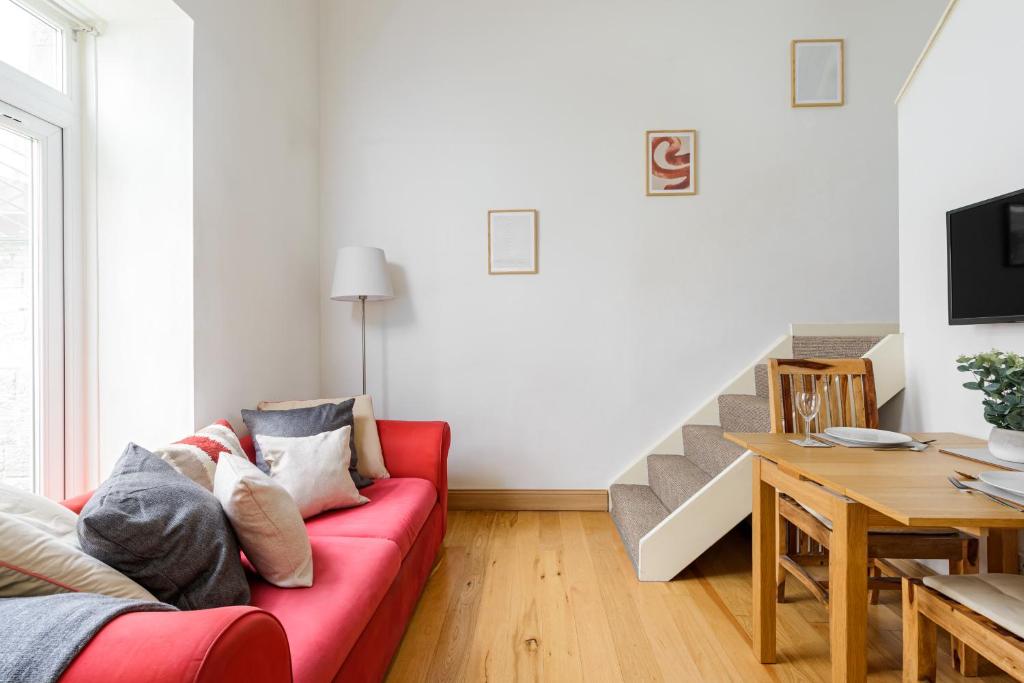 a living room with a red couch and a table at The Old Town Cockburn Apartment in Edinburgh