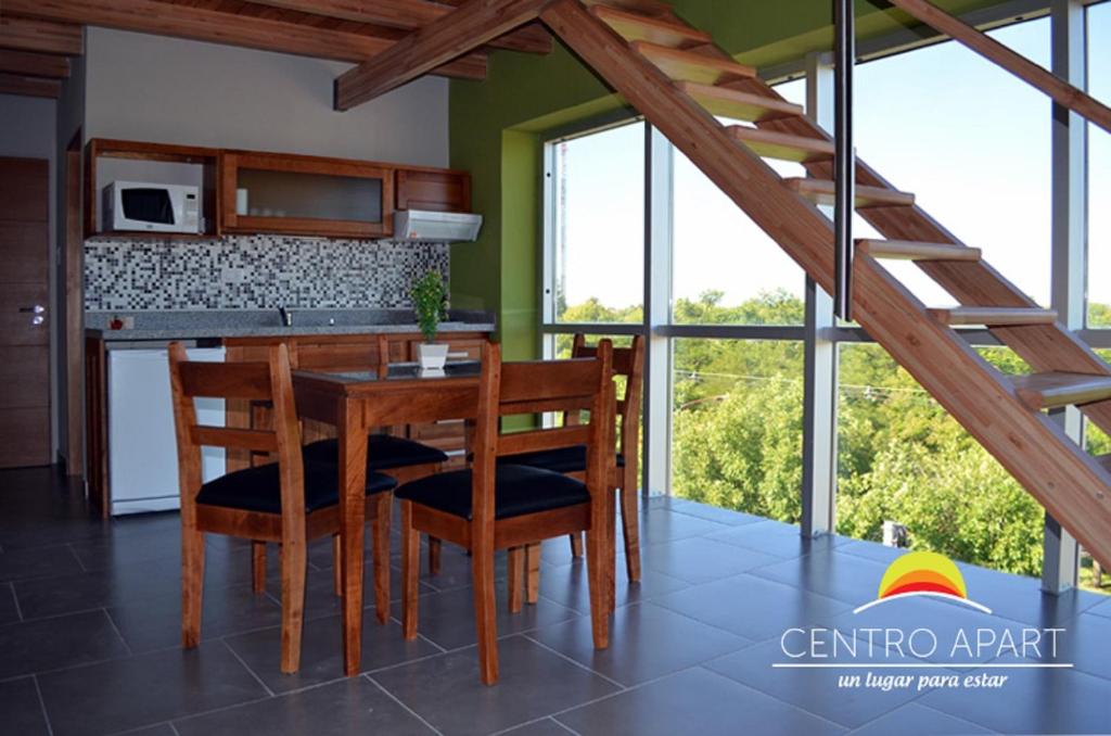 cocina con mesa de madera, sillas y ventanas en Centro Apart en Villa Elisa