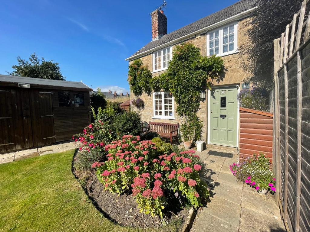 een huis met een groene deur en bloemen in de tuin bij Cottage en-suite room with private lounge in Bridport