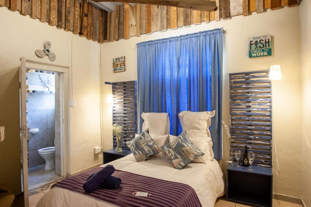 ケープタウンにあるStrand Family studio en-suite 6 sleeper Kitchenette Helderberg CTのベッドルーム1室(青いカーテン付きのベッド1台付)