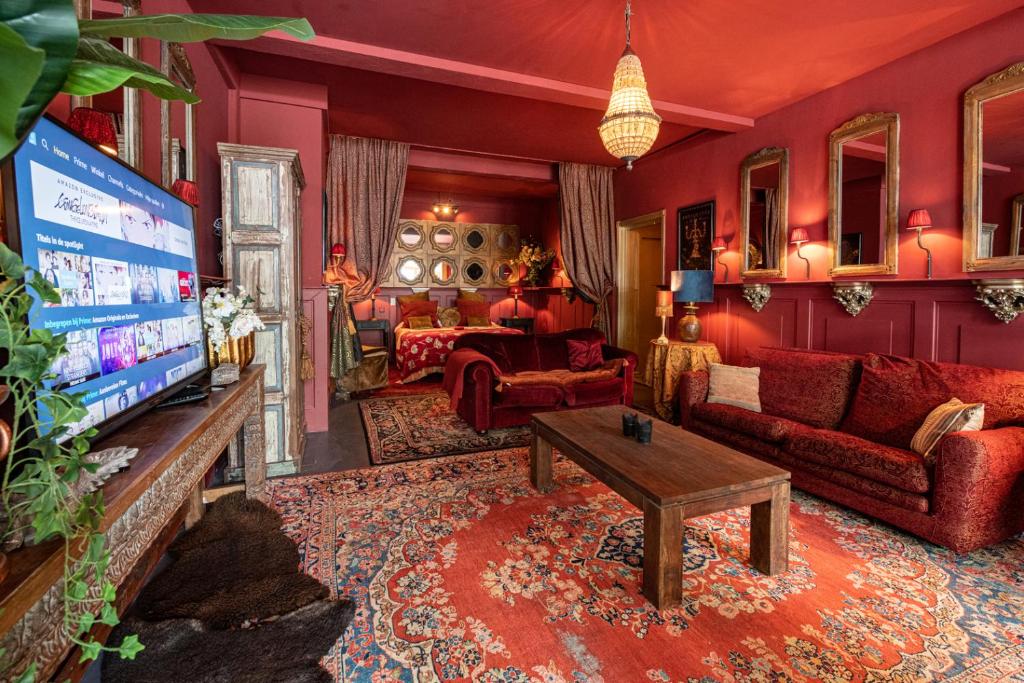 a living room with red furniture and a tv at Herberg De Swaen in Vuren