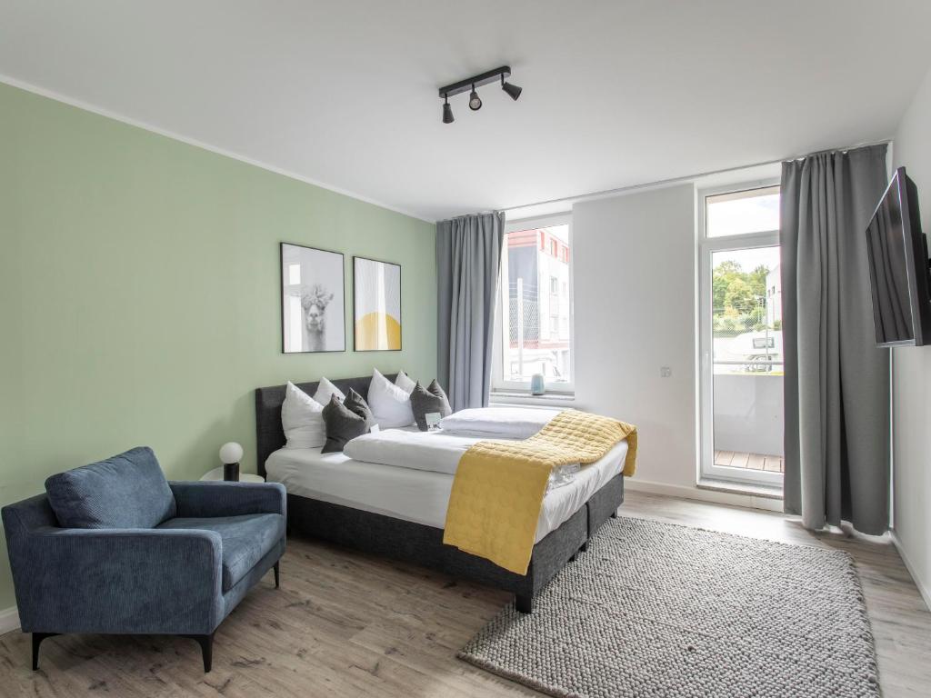 a bedroom with a bed and a blue chair at limehome Chemnitz Hartmannstraße in Chemnitz