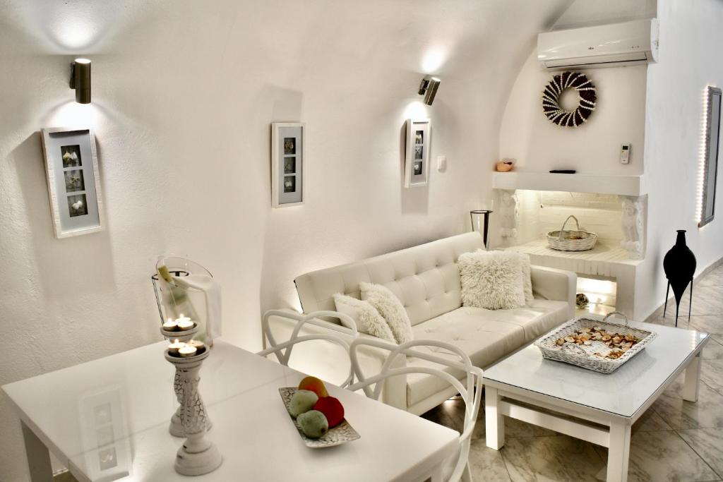 a living room with a white couch and a table at Aeolos Art & Eco Suites Adults Only in Imerovigli
