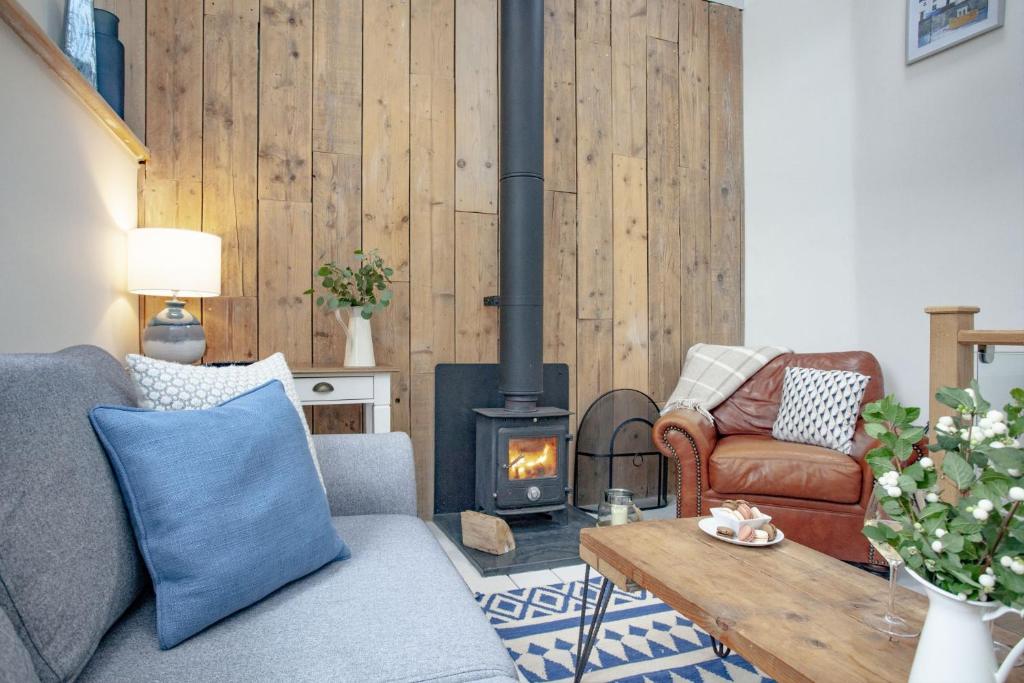 a living room with a couch and a wood stove at Birdcage Cottage, Kingsand in Kingsand