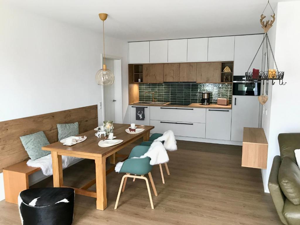a kitchen and living room with a wooden table and chairs at LÜFTLE neue gemütliche große Familien Ferienwohnung im Allgäu in Wolfegg