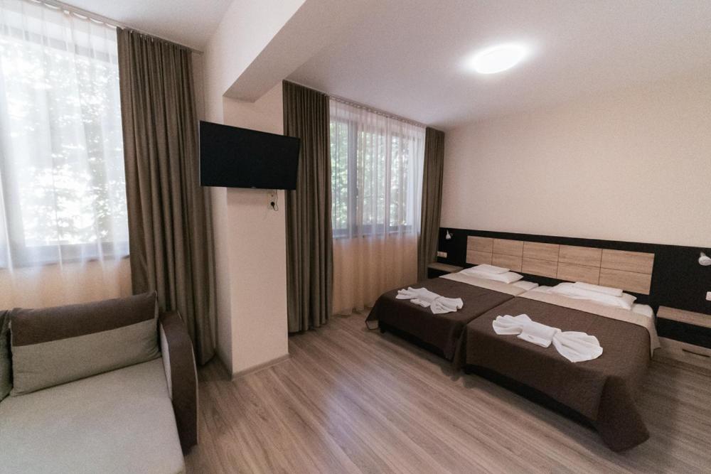 a hotel room with two beds and a couch at Hotel Terra in Gorna Oryakhovitsa