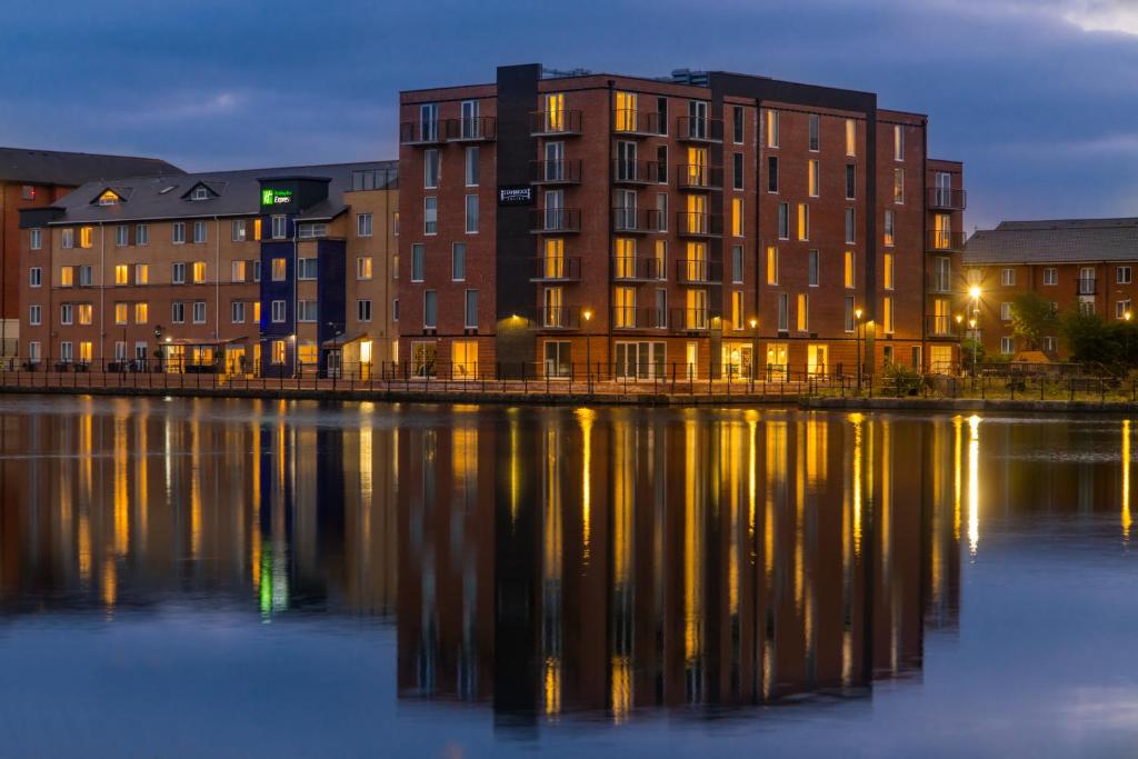 un edificio junto a un cuerpo de agua por la noche en Staybridge Suites - Cardiff, an IHG Hotel, en Cardiff